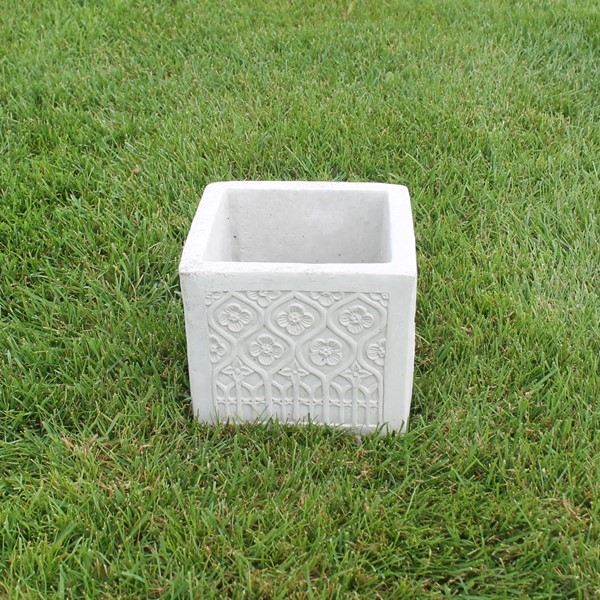 A small square planter with a flower design on all four sides. 