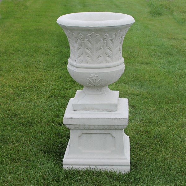 An urn style planter with a fern leaf design on the exterior paired with the small base. 