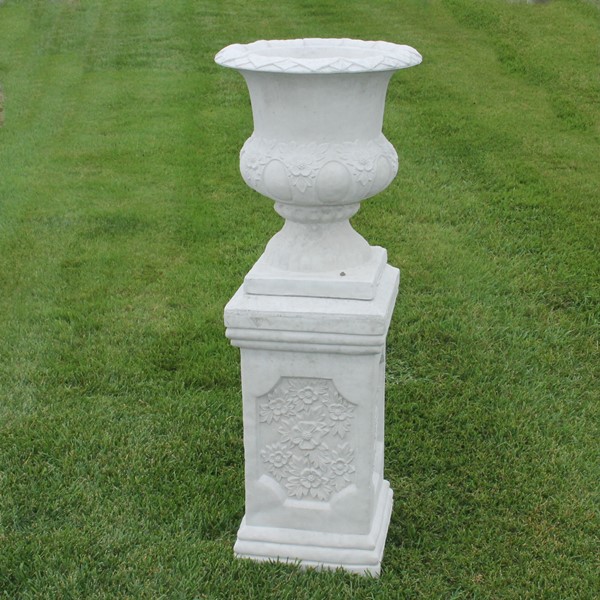 An urn styled planter with decorative flowers in the details. 