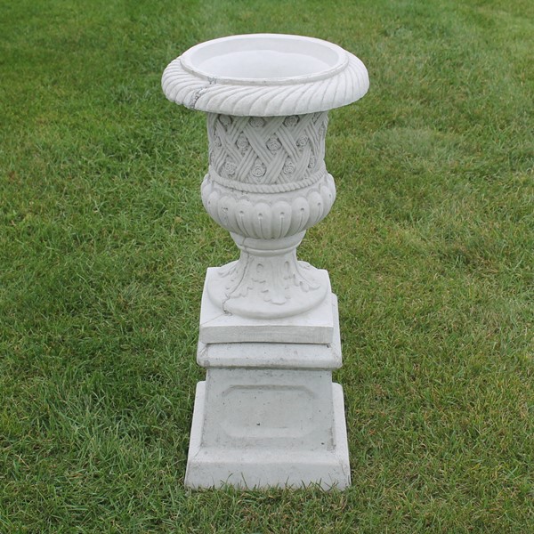 The urn style planter with small little rosettes and a lattice like design to the exterior sitting on a small base